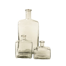 Three clear glass bottle vases of different sizes on a white background