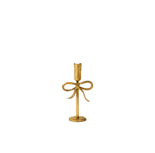 Short gold candle holder with bow design on a white background