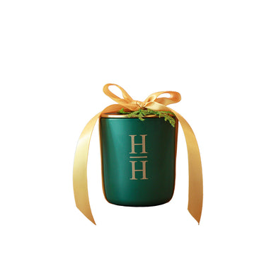 Green candle with gold ribbon and 'HH' logo on a white background