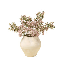 Artificial flower branches with pink flowers and green leaves in a vase on a white background