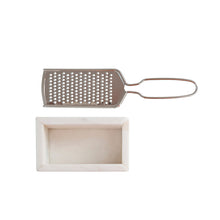 stainless steel cheese grater and white marble container on a white background