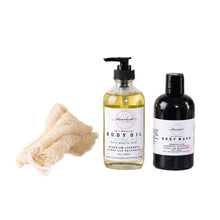 Body oil, body wash, and loofah on a white background