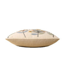 floral embroidered patterned pillow on a beige base on its side on a white background