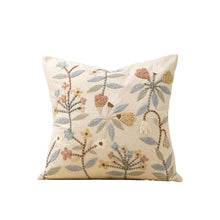 floral embroidered patterned pillow on a beige base on a white background