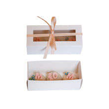 White gift box with a pink ribbon and "mom" truffles inside on a white background