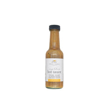 orange habanero  hot sauce in a glass bottle with a white background