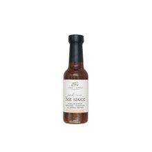 Peach and onion hot sauce in a glass bottle with a white background