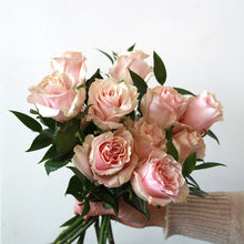 Handheld bouquet of pink roses against a light background