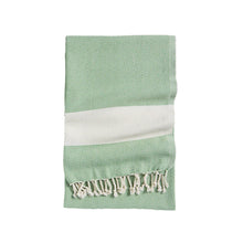 Green towel with white geometric pattern and tassels on a white background