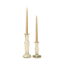 Two clear glass candlestick holders with taper candles on a white background
