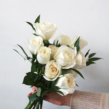 Handheld bouquet of white roses against a light background