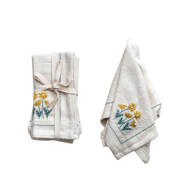 folded white napkins with yellow and green flower embroidery design 
